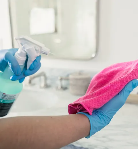 merry maid spraying cleaner on a pink cloth
